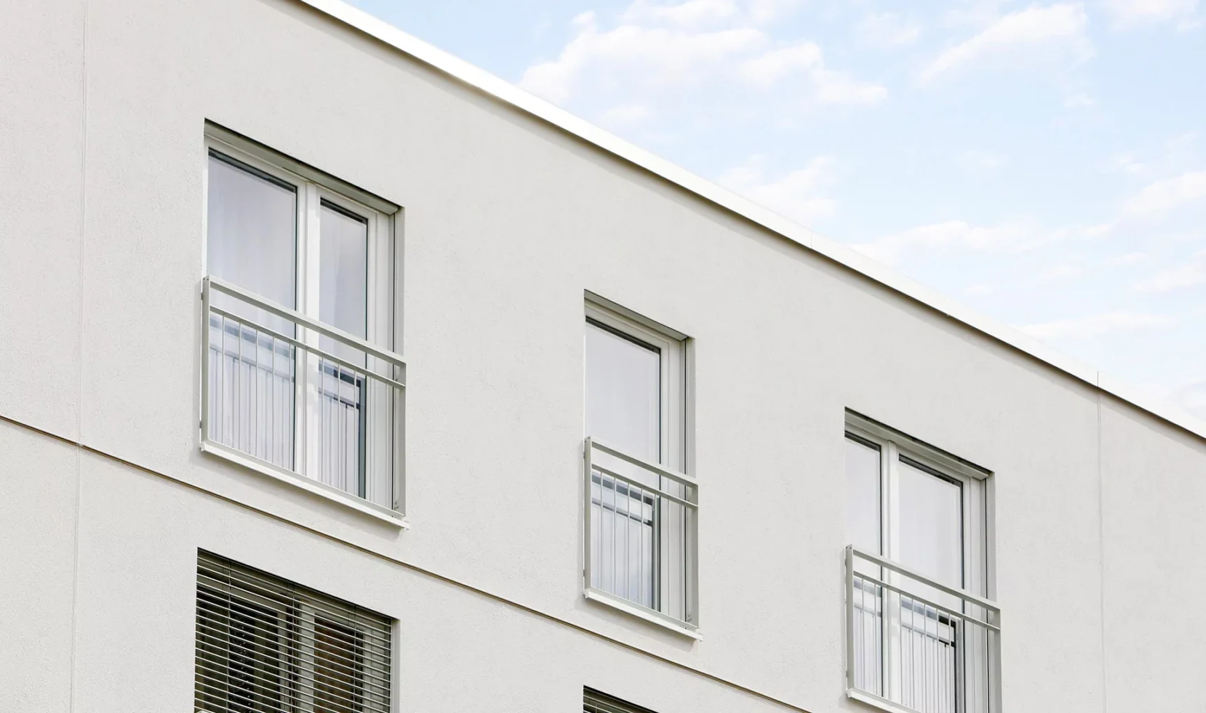 Fenster hinter Absturzlösungen in einer modernen hellen Fassade.