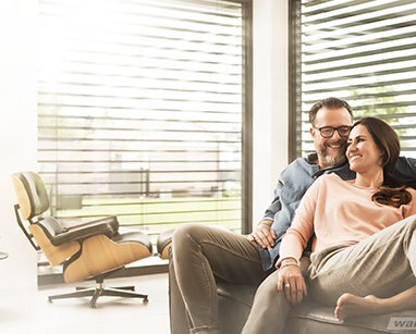 Ein glückliches Ehepaar in einem modernen Wohnzimmer mit schützenden Außenjalousien.