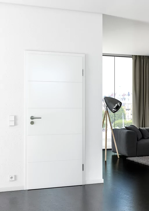 Eine Innentüre mit weißen Blöcken in einem Raum mit weißen Wänden und dunklem Boden und Möbeln.