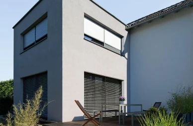 Haus mit Jalousien und Rollladen vor den Fenstern