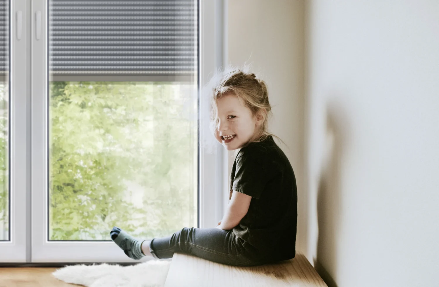 Kind sitzt auf Fensterbank und blickt hinaus